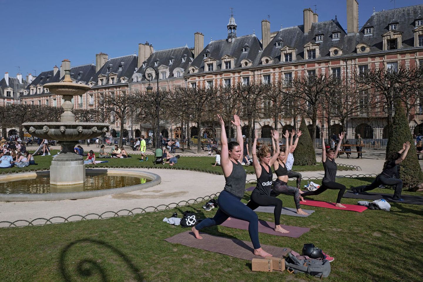 在马克龙即将宣布新一轮封锁政策之前的3月31日，巴黎孚日广场（Place des Vosges）上有民众在晴朗蓝天下上做瑜伽。（Getty）