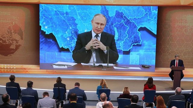 Vladimir Putin on a screen in front of an audience