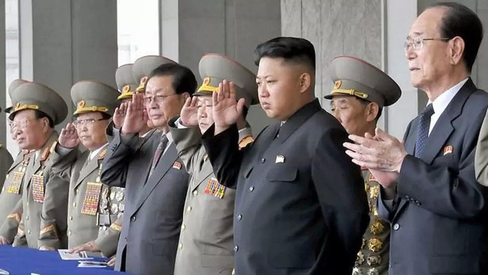 Kim Jong-un, en costume sombre. Son oncle est à sa droite, en costume cravate
le 23 décembre 2013