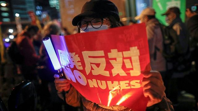 日本反核示威者在东京电力公司东京总部外举起“反对原发”标语牌（11/3/2021）