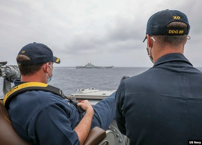 美国海军马斯廷号驱逐舰的舰长罗伯特·布里格斯中校（Robert J Briggs）与副舰长理查德·斯莱中校（Richard D Slye）2021年4月4日在菲律宾海域正在导航室外监视中国航母辽宁号。（美国海军提供）