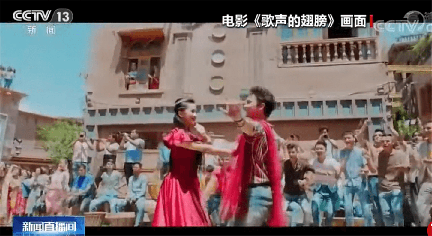 在《歌声的翅膀》电影片段中，新疆的年轻男女们聚集在一起唱歌舞蹈。（中国央视截图）