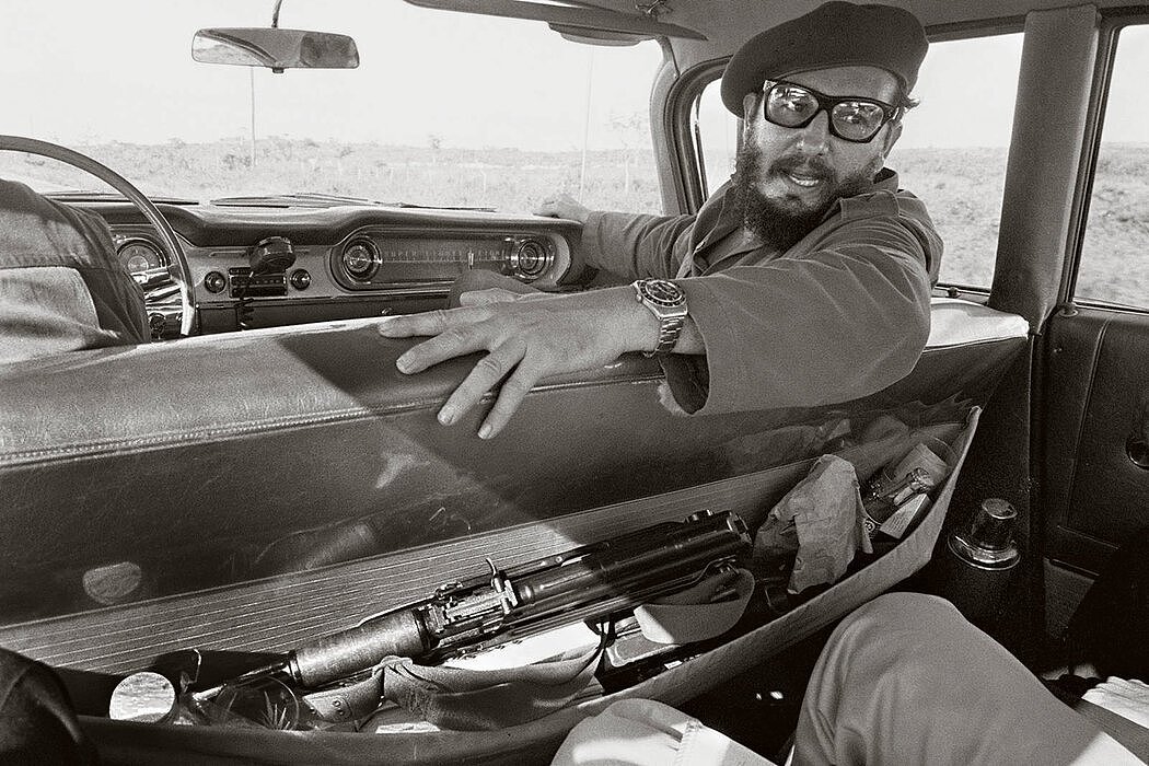 1964年，菲德尔·卡斯特罗在一辆车上接受记者采访。座椅口袋里放着一把突击步枪。