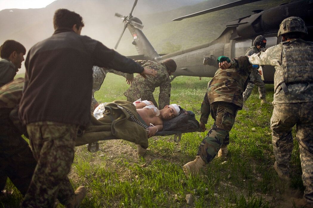 2010年3月，库纳尔省，阿富汗士兵将一名受伤的警察送往一架美国直升机。