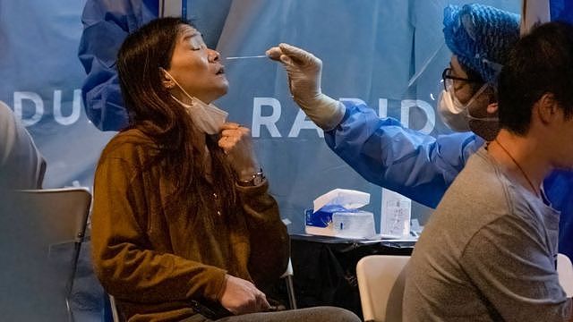 医护人员在香港九龙油麻地一处临时封锁区内给一位居民采样检测新冠病毒（4/2/2021）