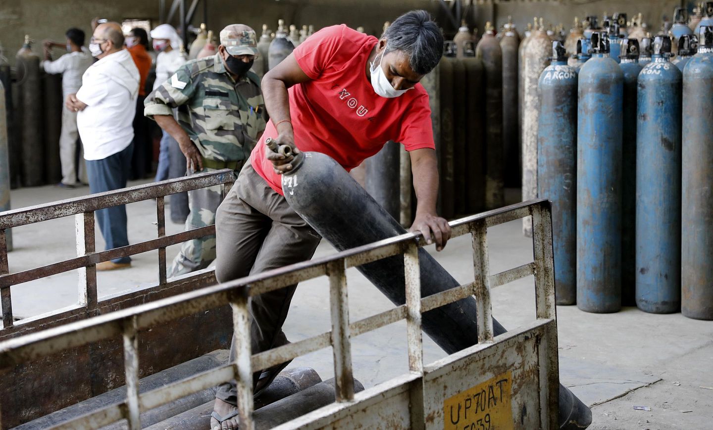 印度氧气全面告急。图为2021年4月23日，工人在印度Prayagraj郊区的充电站装载氧气瓶。（AP）