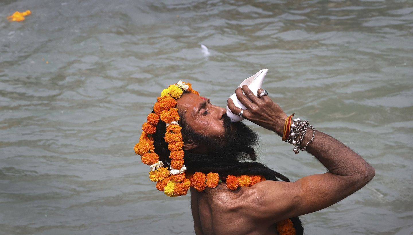 在2021年4月12日在印度北阿坎德邦北部的哈里瓦尔，在大壶节期间，一名印度教教徒在恒河中吹海螺壳。（AP）