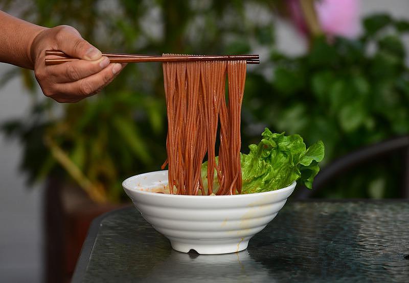 广西柳州市一家螺蛳粉店里，工人在展示新上市的红高粱螺蛳粉。 (新华社)