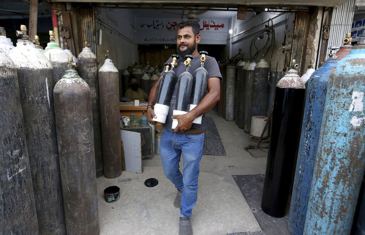 4月26日，卡拉奇一名男子在一间商店为氧气瓶充气后，捧着它们离去。（AP）