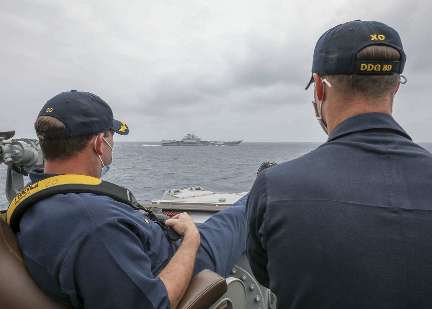 美国海军官网此前发布两位军官眺望辽宁舰的照片，左边的美军驱逐舰舰长正“翘腿”观望。（美国海军官网）