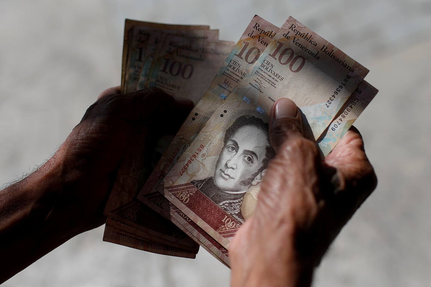 委内瑞拉2019年经济恶化到被迫美元化，再加上当地本就苦于经济崩溃与恶性通脤，对该国民众帮不上多少忙。 图为2018年1月，一名男子在委内瑞拉加拉加斯数钱。 他在点算的是该国货币玻利瓦。 （Reuters）