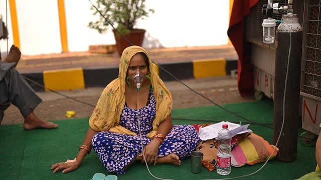 印度新德里一座锡克庙内一位怀疑感染新冠病毒的女士坐在地上吸氧（1/5/2021）