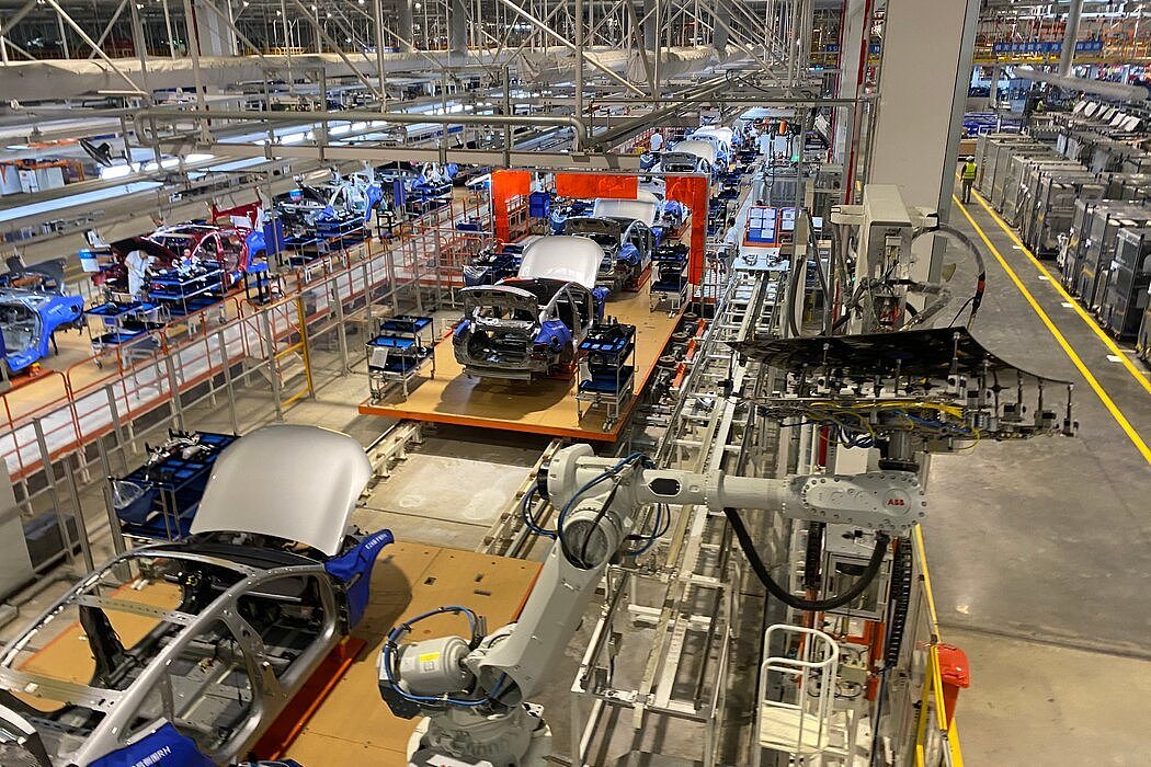位于中国肇庆的小鹏汽车高度自动化的工厂，一个机器人举起有色玻璃固定在车顶。