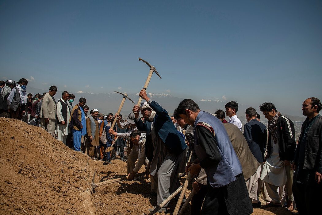 男人们轮流为在爆炸中丧生的数十名女孩挖掘坟墓。