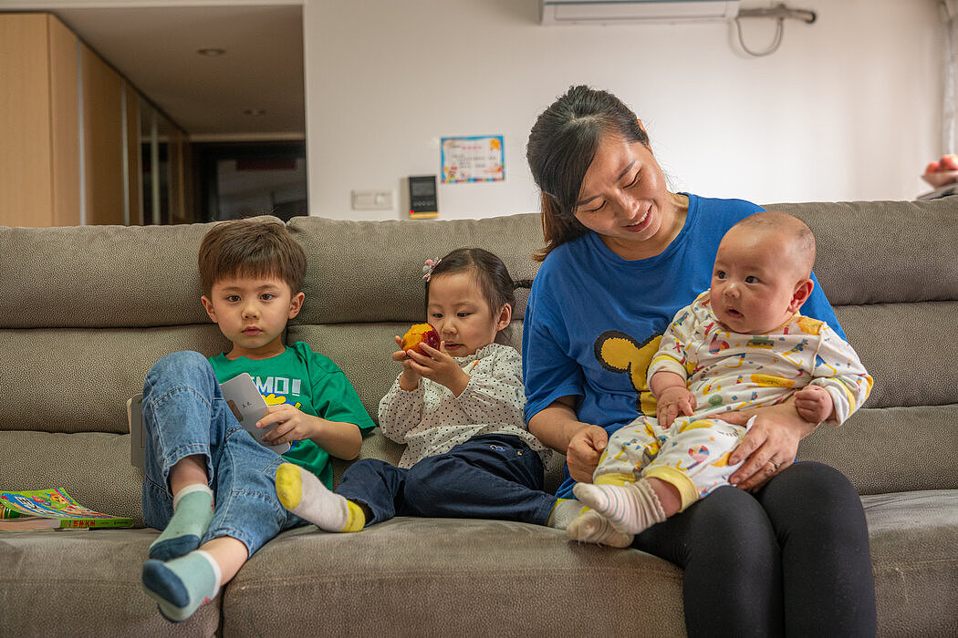 在中国东莞，陈华云（音）和她的孩子志豪（左，音）和淑薇（中，音），以及4个月大的家豪（音）。今年，陈华云不必隐瞒第三个孩子的出生。