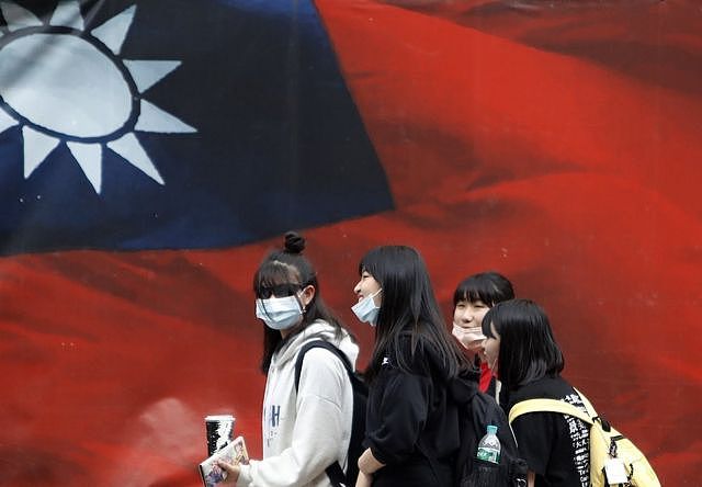 戴着口罩的台湾女生走过中华民国国旗（2021年4月11日资料照片）