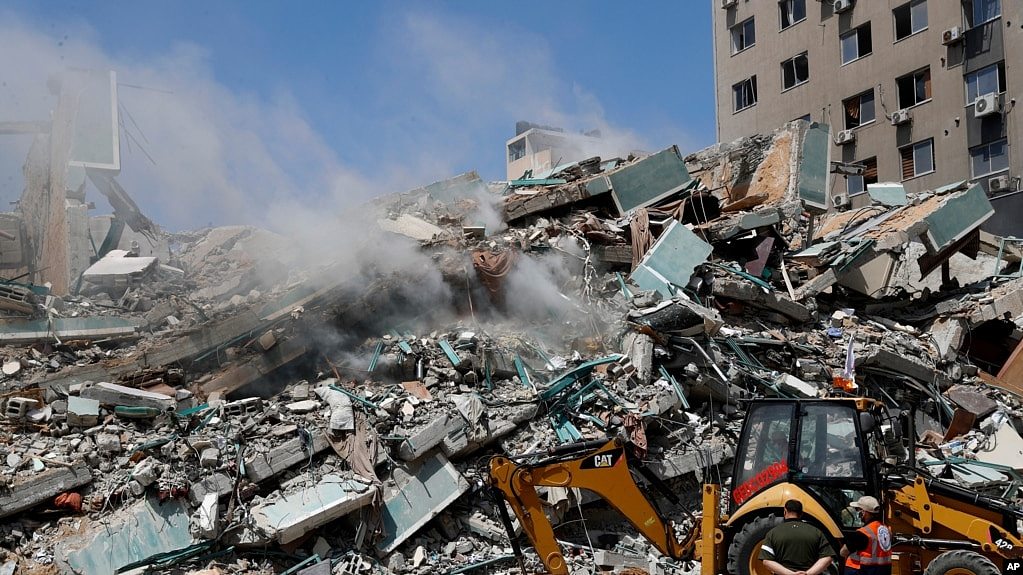 工人们正在清理以色列周六空袭摧毁的一座大楼的瓦砾。美联社、半岛电视台等媒体的记者站就设在加沙市的这座大楼里。（美联社照片，2021年5月16日）