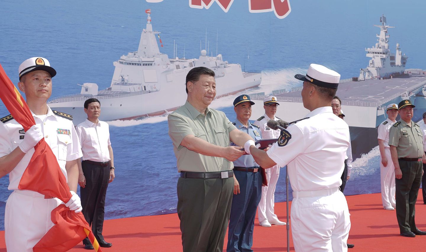 2021年 4月23日，中国一次入列海军三型主战舰艇——长征18号艇、大连舰和海南舰。图为中国国家主席习近平向海南舰授予军旗、命名证书。（新华社）