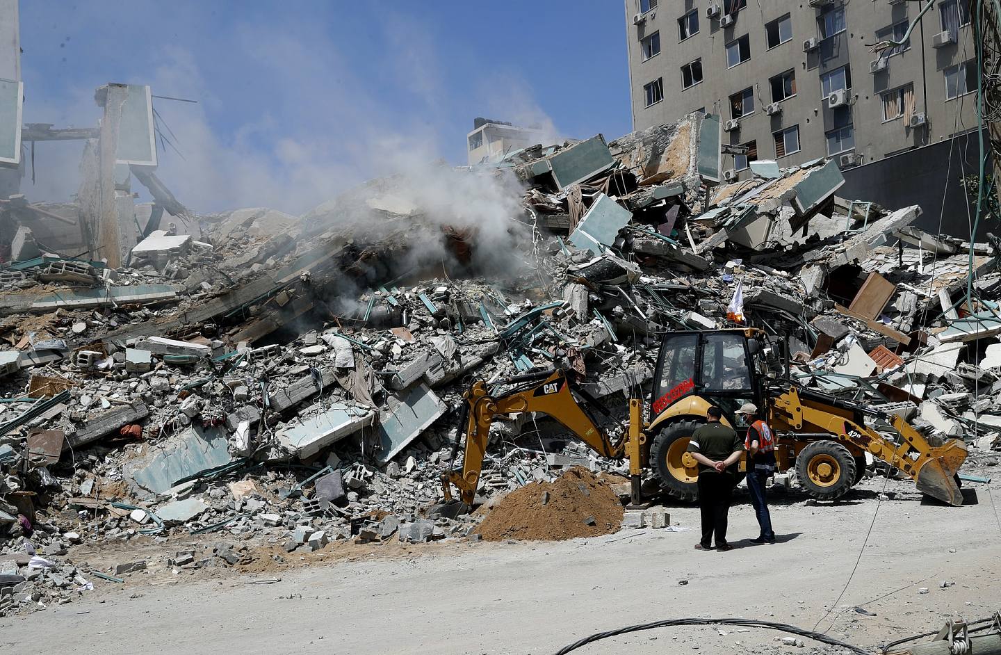 以巴冲突：以色列军队炸毁加沙一栋大楼，令它倒塌。 图为5月16日，工人清理瓦砾堆。 这栋大楼是数家国际传媒的办公室所在地。 （AP）