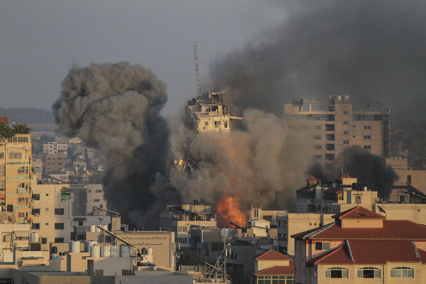 5月12日，加沙城一处建筑在以色列空袭中倒塌，现场升腾起浓烟。（新华社）