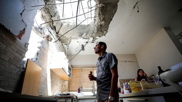 Adi Vaizel, looks at the damage caused to the kitchen of his house after it was hit by a rocket launched from the Gaza Strip