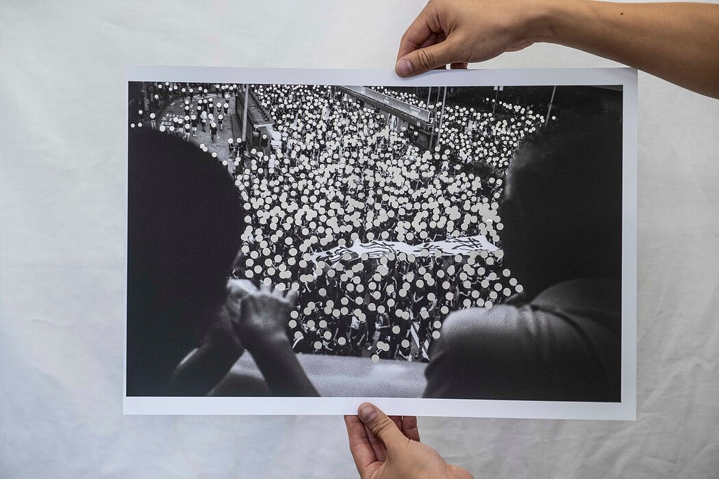 萧伟恒的作品，展示了一张2019年抗议活动的照片，上面有被剪掉的面孔。