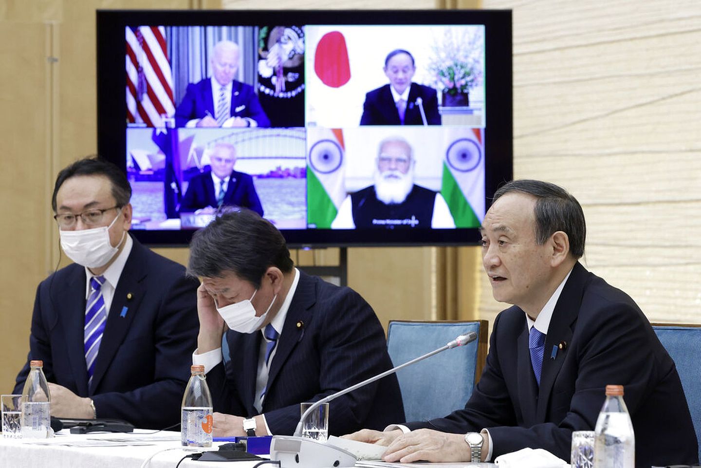 2021年3月12日，日本首相菅义伟（右一）在官邸出席四方安全对话视频峰会。他身后的电视屏幕分别显示美国总统拜登（左上）、印度总理莫迪（Narendra Modi，右下）和澳大利亚总理莫里森（Scott Morrison，左下）出席会议的情景。（AP）