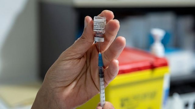 医护人员正将疫苗从小瓶中抽入注射器