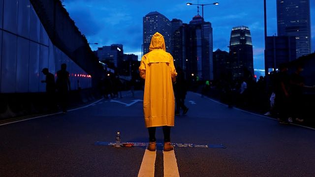 A protester wears a yellow raincoat to pay tribute to a man who died after falling from a scaffolding at the Pacific Place complex while protesting against the extradition bill, during a demonstration demanding Hong Kong