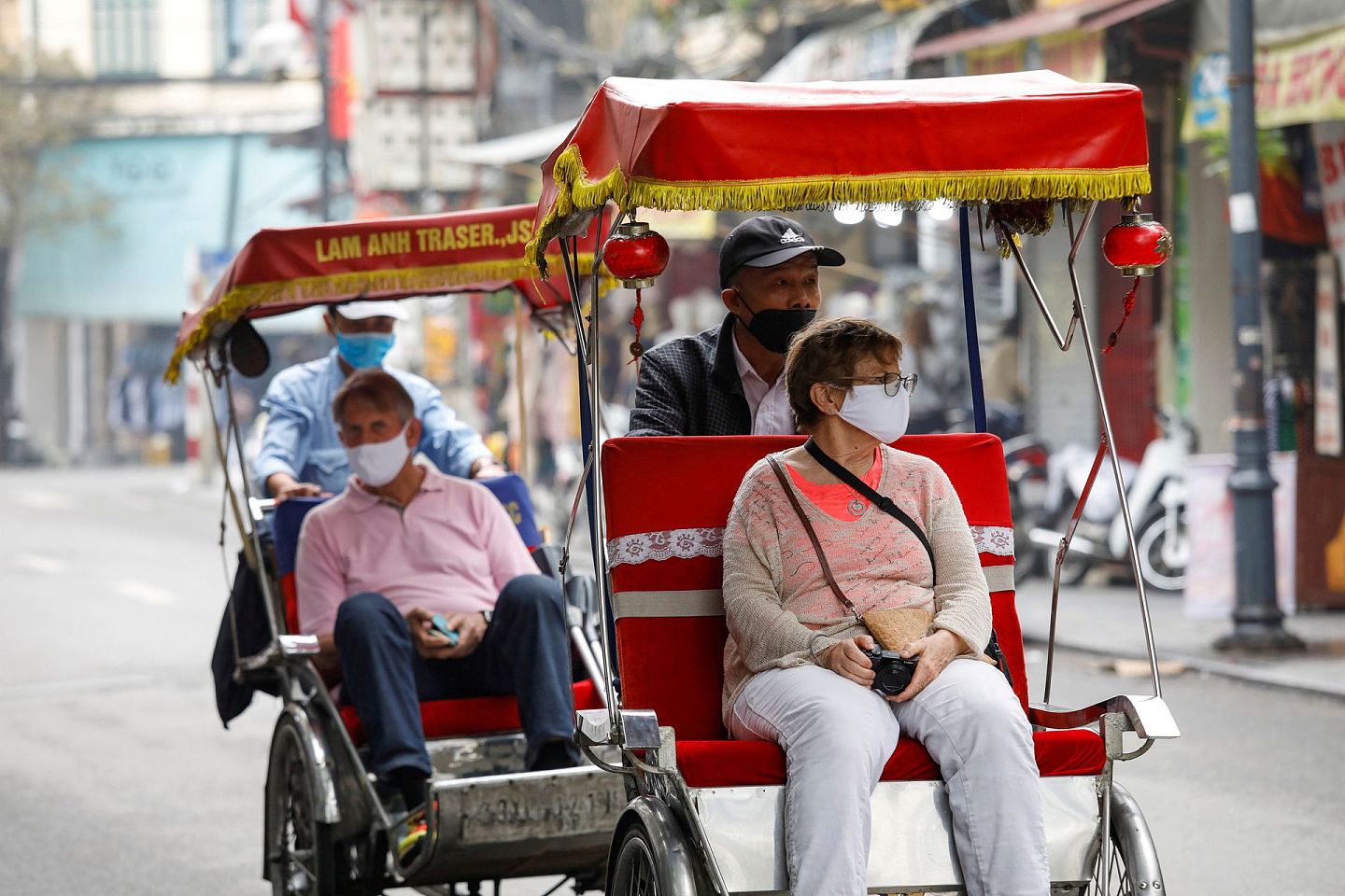 两名外国游客在2020年3月时戴着口罩，搭乘载客三轮车徜徉于越南河内老城区的街道。此后，越南开始了更为严格的封闭与防疫措施，到2020年6月，越南全境只接纳了约九千名外国旅游者。此举让越南的旅游业陷入冰点。虽然此后岘港短期开放，但随之而来的疫情更为难以收拾。（路透社）