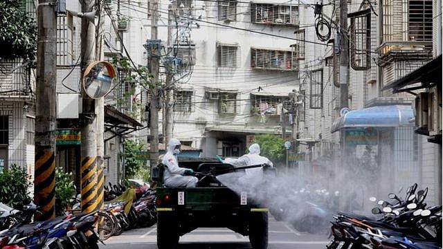 身穿防护服的军人在台北街头消毒。
