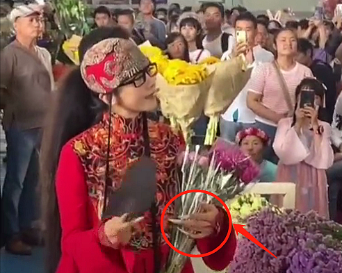 63岁杨丽萍逛花市被拍！身形消瘦长指甲抢镜，男伴贴心为其提袖子