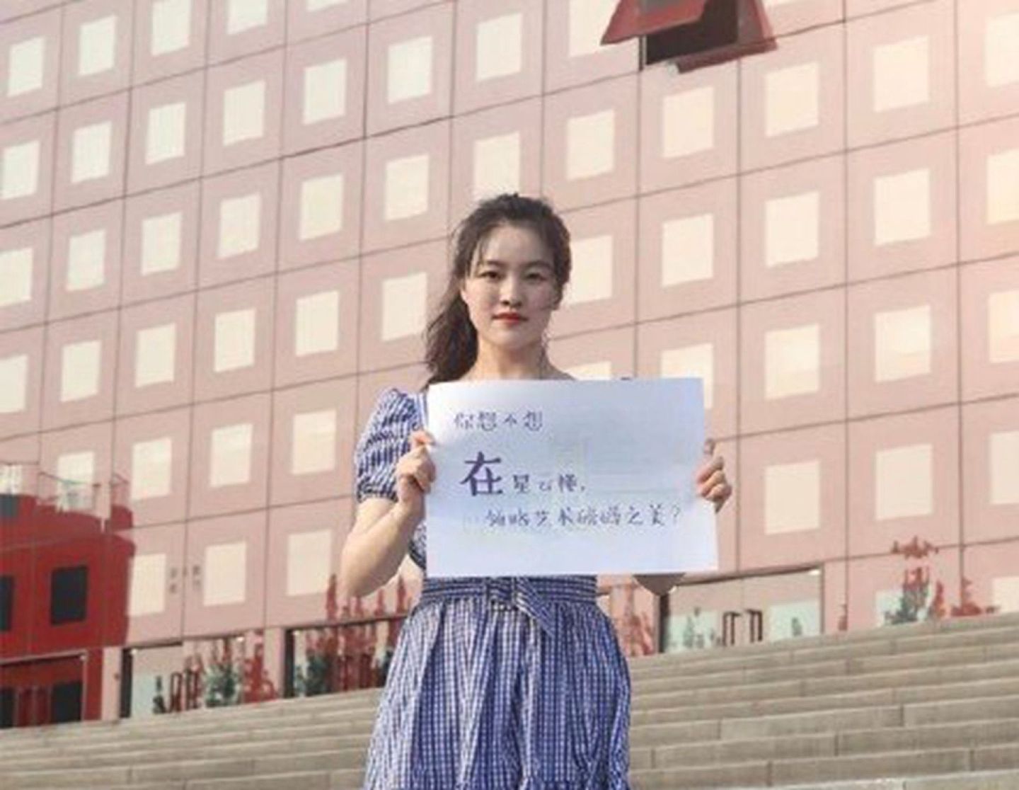 女生站在南京大学校内，手里举着招生宣传牌。（微博@林中白狼）