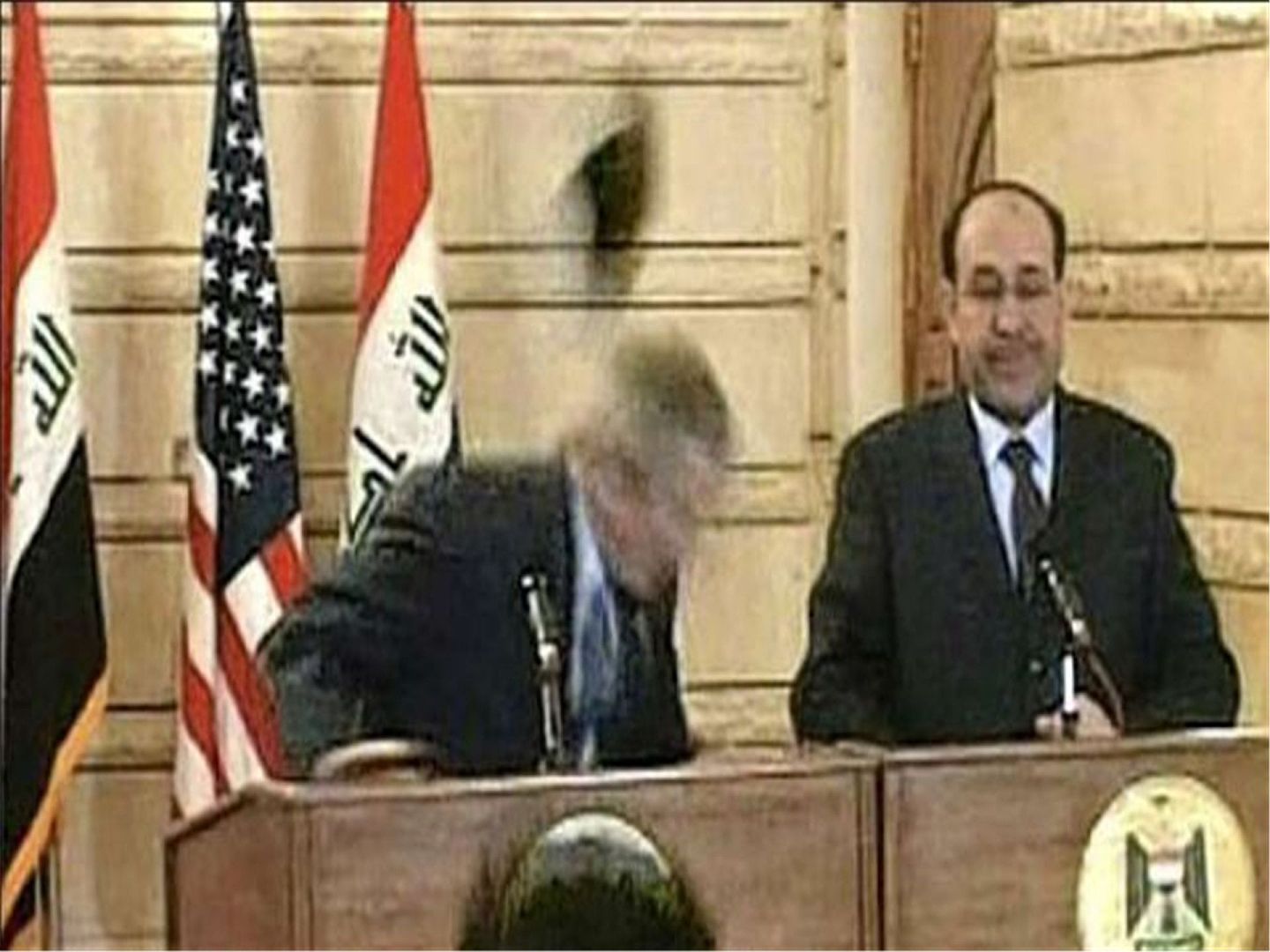 就在小布什准备发言时，一名记者突然脱下自己的鞋子，向小布什砸去。（维基百科公有领域）