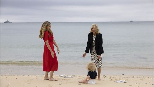 拜登夫人和约翰逊夫人在卡比斯湾的沙滩上脱掉鞋子在海滩陪伴约翰逊夫妇的儿子。