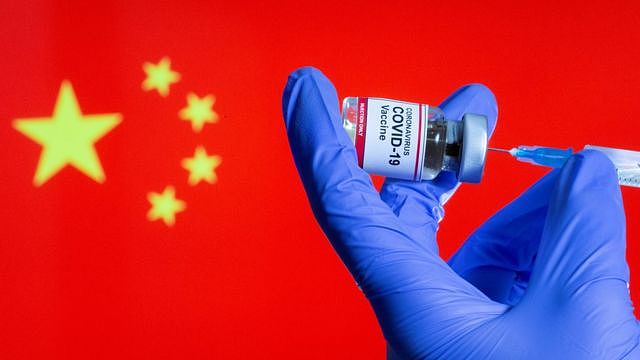 设计图片：一位女护士在中国国旗前预备新冠疫苗针剂