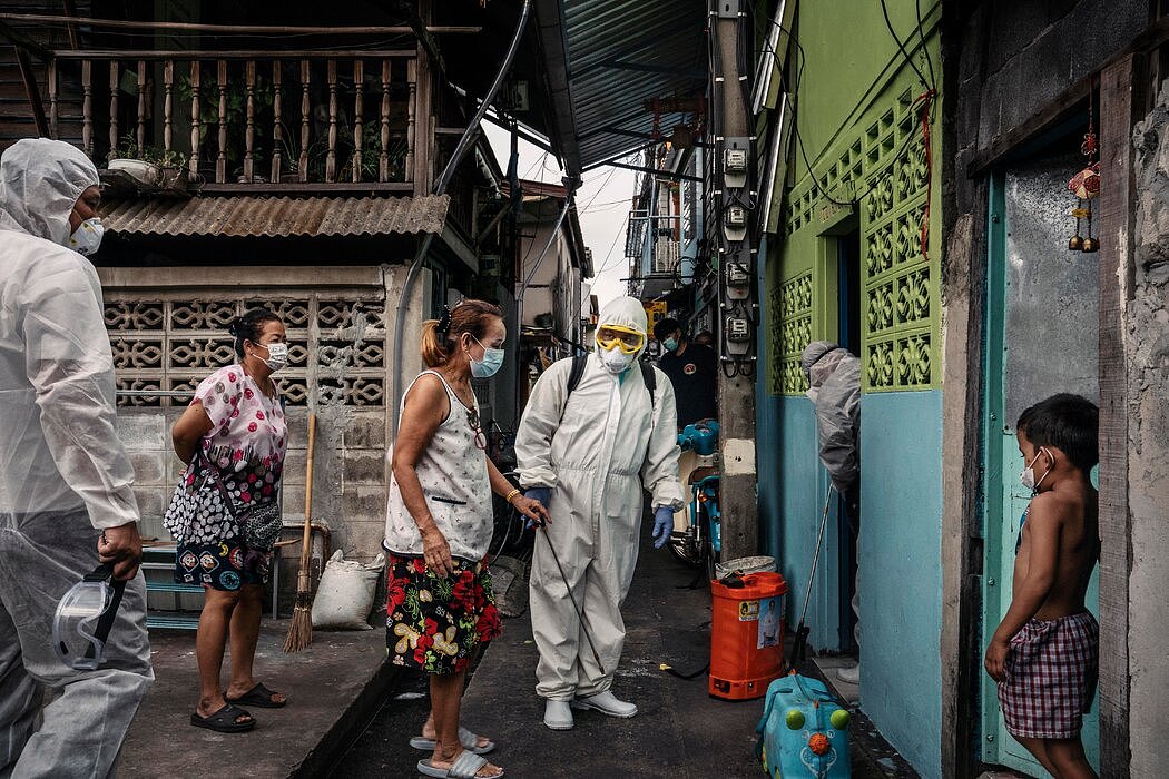 上个月在曼谷，人们准备进入新冠病毒检测阳性者的家中喷洒消毒剂。