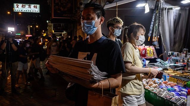 香港九龙旺角街头一位男子捧着一叠刚买来的《苹果日报》离开（18/6/2021）