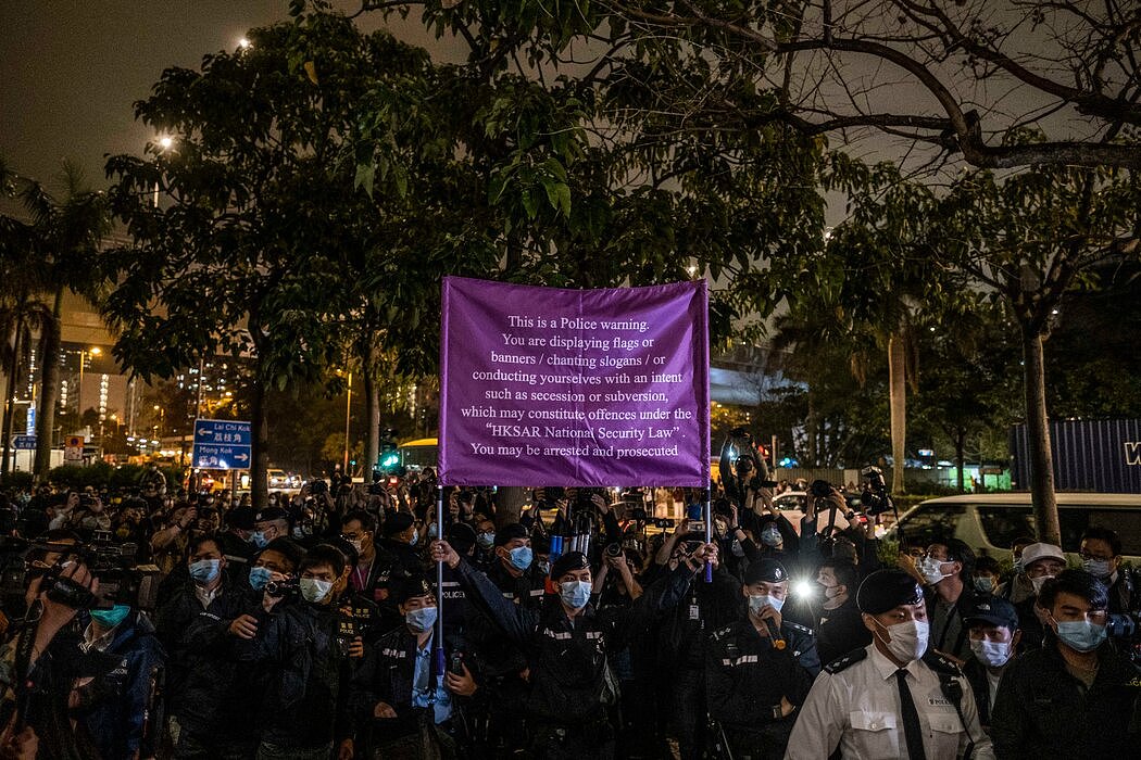 3月，在香港法庭外的抗议活动中，警察举着警告新国家安全法的横幅。