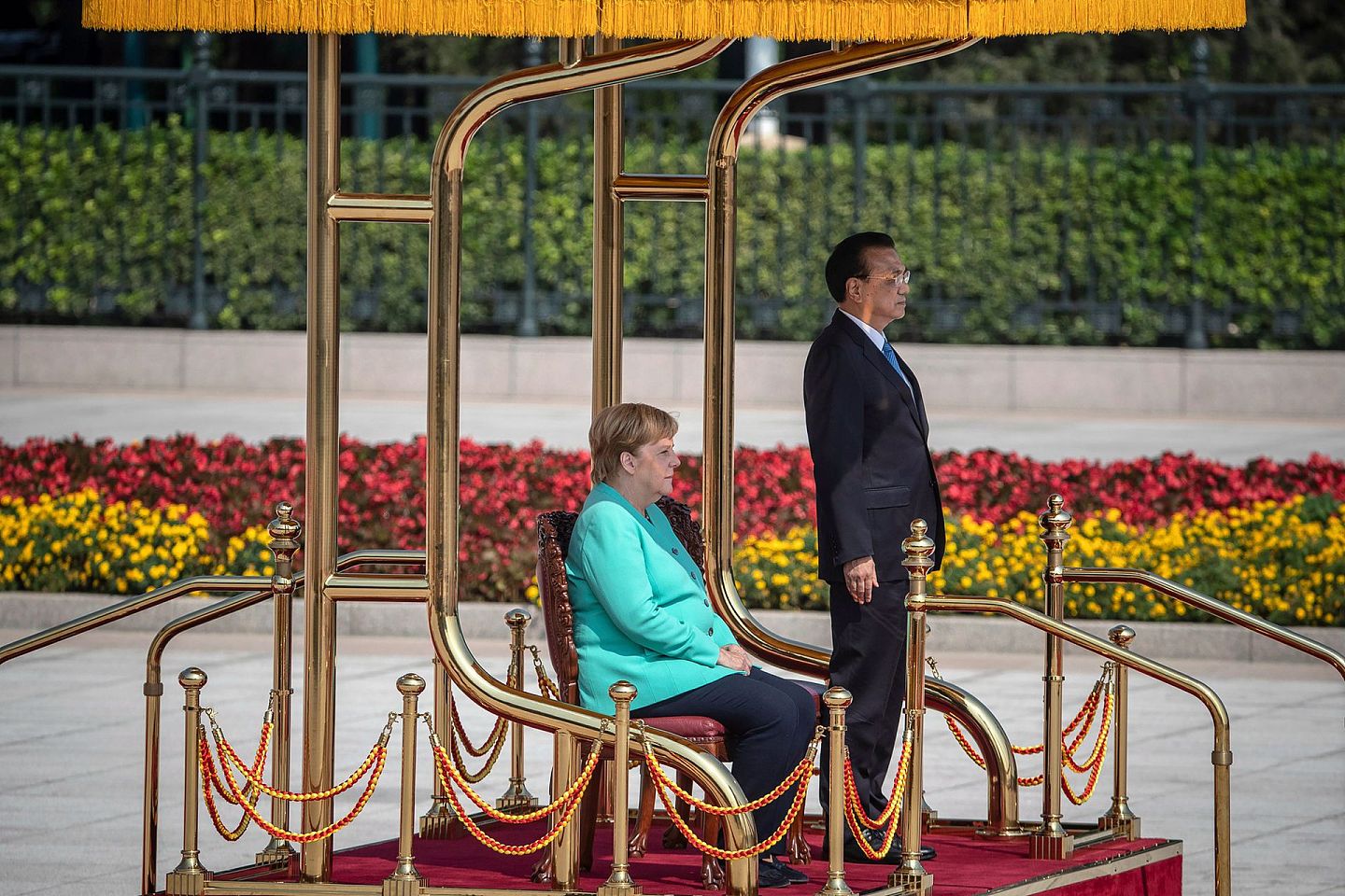 当时，由于默克尔身体不舒服，中国方面在两国领导人检阅仪仗队的地方安排了两把椅子。从欢迎仪式的现场来看，默克尔大多数时间都是坐在椅子上，即便是在奏德国国歌的时候。而李克强在奏中国国歌的时候则起立。（AP）