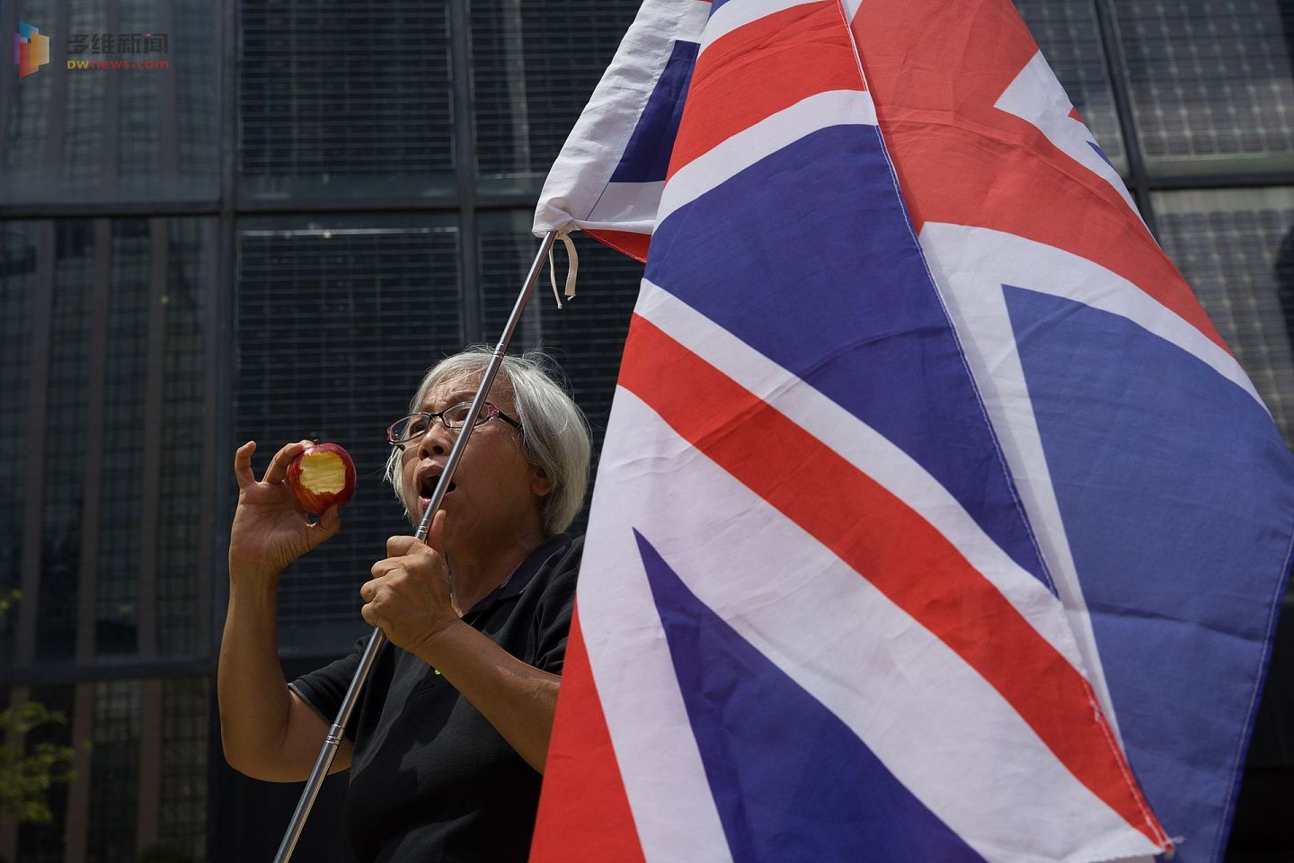 2021年5月28日，香港区域法院宣判黎智英等非法集结案，经常举着英国国旗参加各种香港示威的王婆婆到法院外声援，并拿着一个咬了一口的苹果。（香港01）