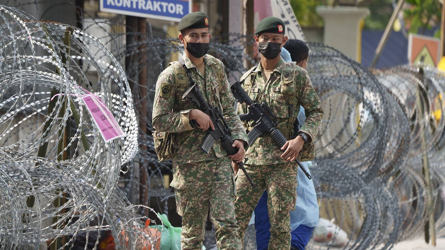马来西亚新冠肺炎疫情：图为6月27日，马来西亚政府在吉隆坡颁布加强行动管制令，军人在封锁区的铁丝网外驻守。 （AP）