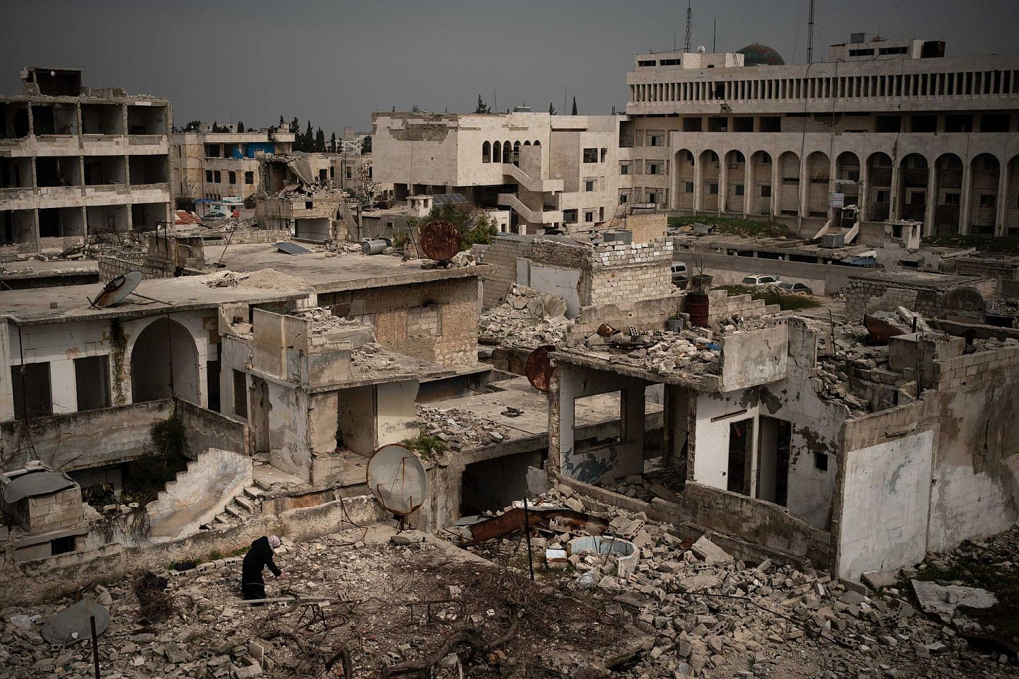 战乱让叙利亚满目疮痍。数据显示，至少38万人在战火中死亡，大约1,200万人流离失所，其中560多万人逃往境外。图为2020年3月12日，一名妇女站在伊德利卜被严重破坏的一座建筑顶部。（AP）