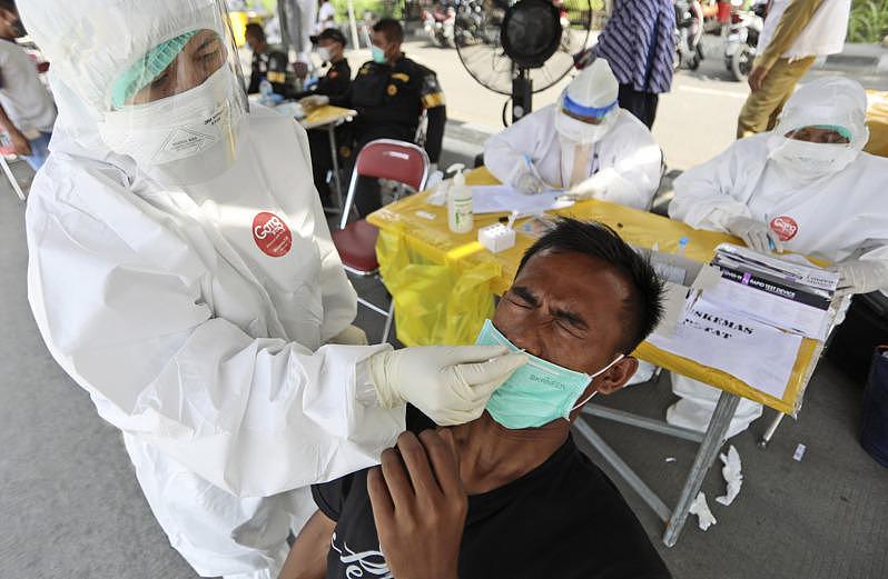 近来印尼新冠肺炎确诊病例激增，图为医护人员正为民众进行新冠筛检。 （美联社）