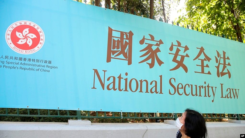 香港一名妇女走过街头的国安法宣传牌（美联社2020年6月30日）