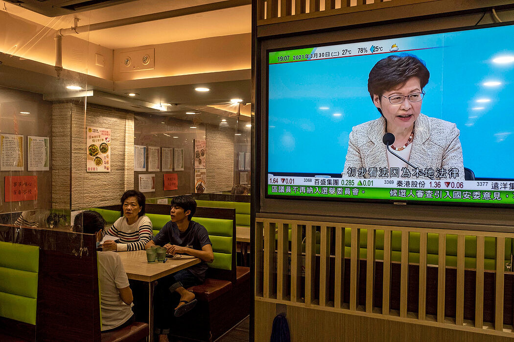 中央宣布对香港选举制度进行全面改革后，当地一家餐馆的电视屏幕上播放着香港领导人林郑月娥出席新闻发布会的画面。