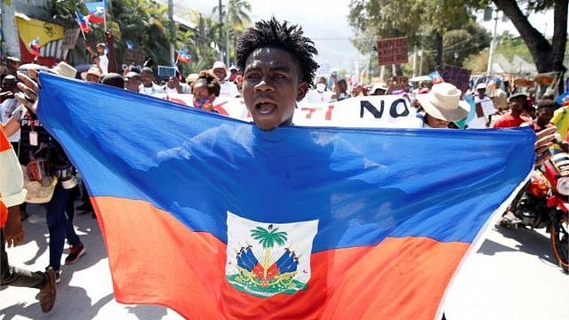 海地太子港一名反莫伊兹示威者展示海地国旗（14/2/2021）
