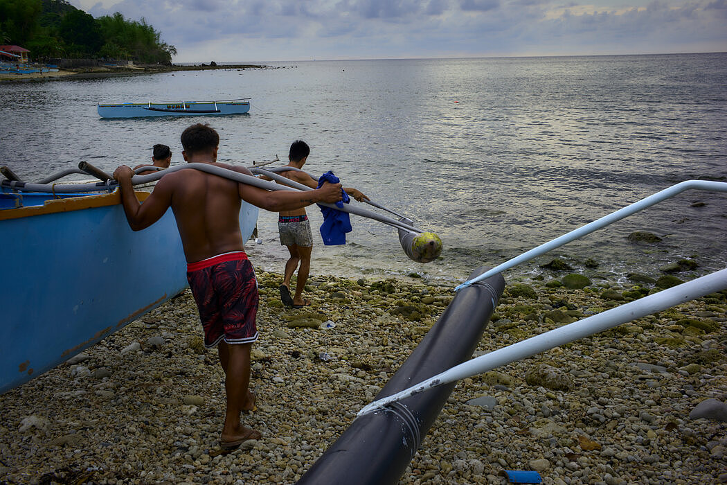 在一天的捕捞之后，奥拉尼的渔民将船只拖上岸边。