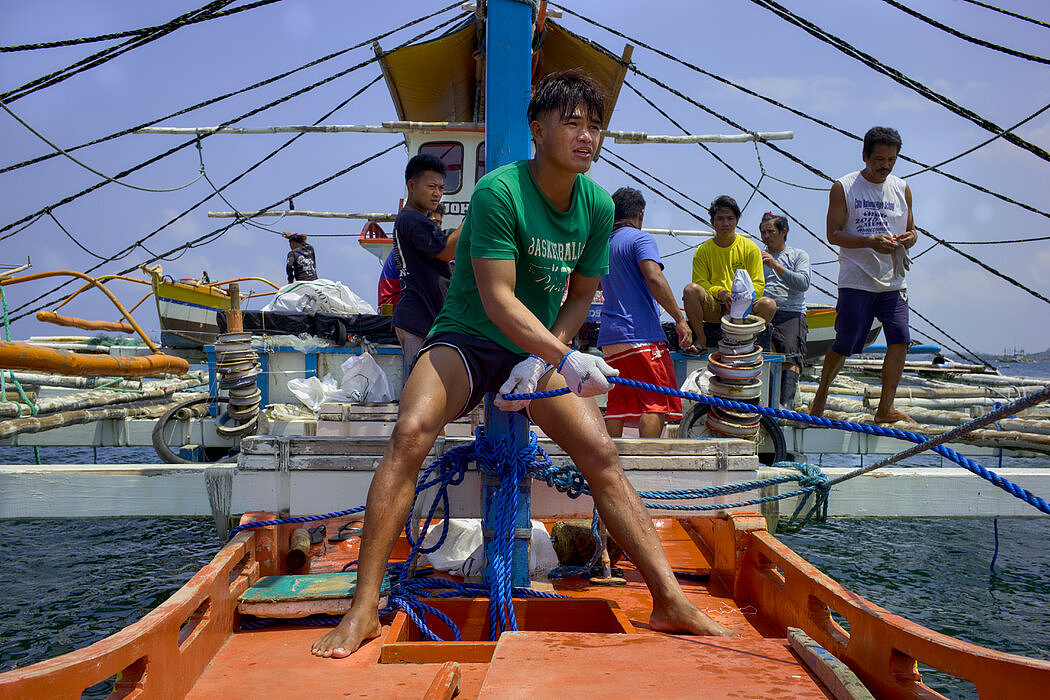 在吕宋岛沿岸的渔业社区马辛洛克，渔民将补给拖到一艘船上。