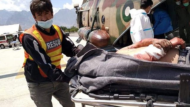 巴基斯坦吉尔吉特一名救援人员把客车爆炸事故生还伤者从直升机卸下（新华社图片14/7/2021）